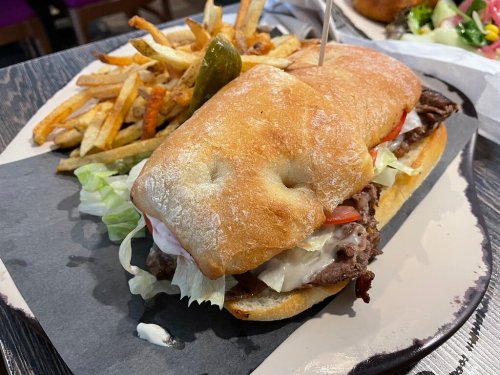 A hearty sandwich with roast beef, lettuce, and tomato, served with crispy fries on the side.
