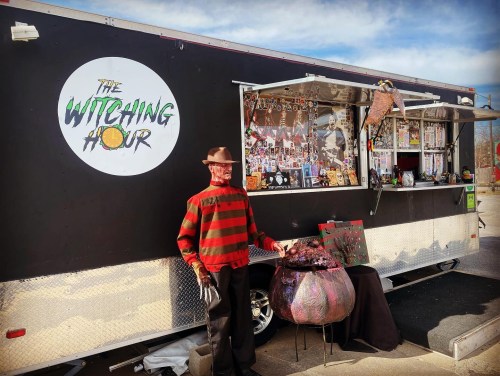 A food truck named "The Witching Hour" features a Freddy Krueger figure and spooky decorations outside.