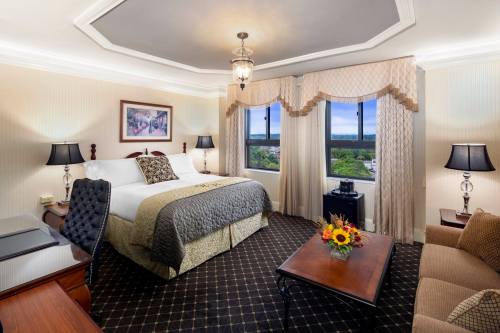 A cozy hotel room featuring a king-sized bed, elegant decor, and large windows with scenic views.