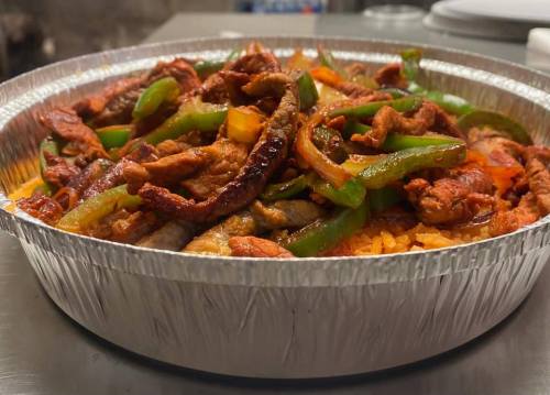 A silver tray filled with seasoned meat, bell peppers, and rice, showcasing a colorful and appetizing dish.