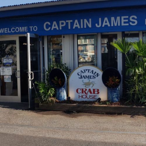 Sign for Captain James Crab House, featuring tropical plants and a welcoming entrance.