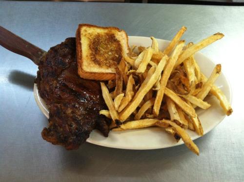 A plate featuring a grilled steak, golden fries, and a slice of toasted bread.