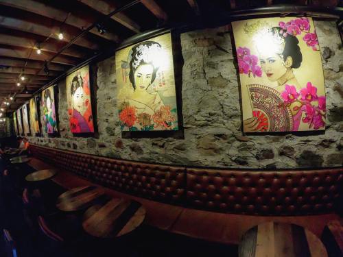 A cozy restaurant interior featuring stone walls and colorful artwork of women surrounded by flowers.