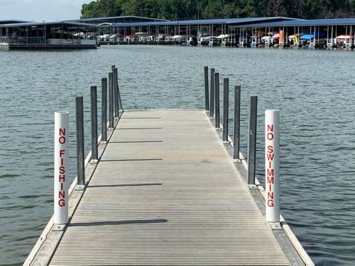 A wooden dock extends over calm water, with signs stating "No Fishing" and "No Swimming" on either side.