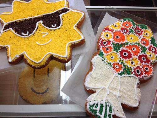 Two colorful decorated cookies: one shaped like a sun with sunglasses, the other resembling a bouquet with flowers.