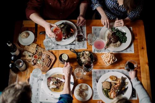 A top-down view of a dining table with various dishes, drinks, and people enjoying a meal together.
