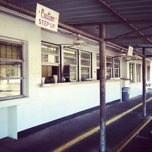 A building with a long counter and multiple windows, featuring signs that say "Caution" and "Step Up."