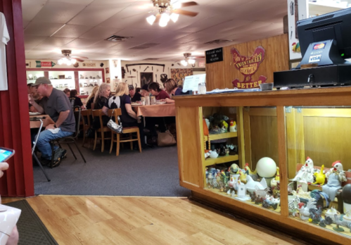 A cozy restaurant interior with diners at tables and a display case filled with decorative items.