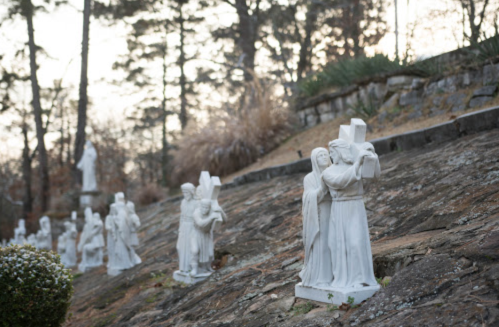 A hillside with white statues depicting religious figures, surrounded by trees and greenery.