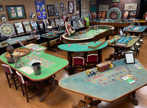 A vintage casino interior featuring various gaming tables, slot machines, and memorabilia on the walls.