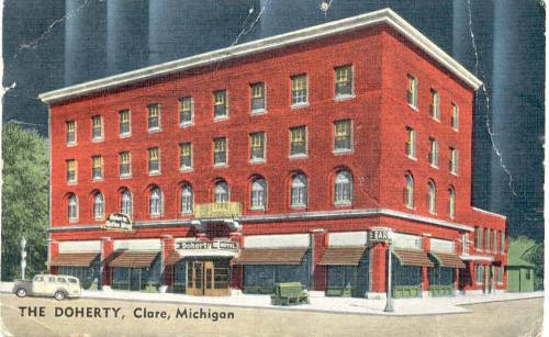 A vintage postcard of The Doherty Hotel in Clare, Michigan, featuring a red brick building and classic storefronts.