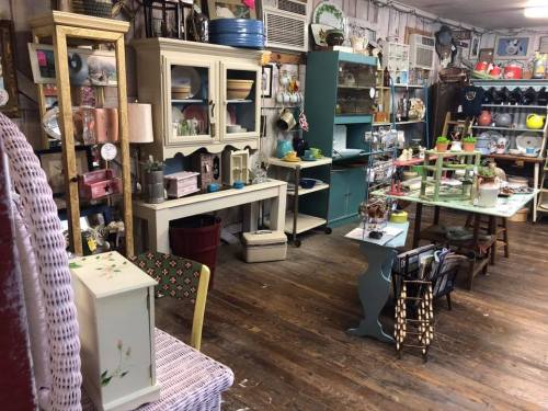 A cozy vintage shop filled with colorful furniture, decor items, and various collectibles on wooden floors.