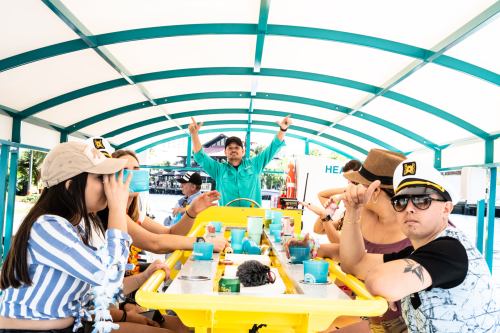 A group of people enjoying a meal on a colorful boat, with one person enthusiastically raising their arms.