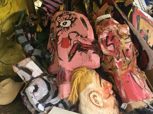 A pile of colorful, abstract sculptures and masks with exaggerated facial features and expressions.