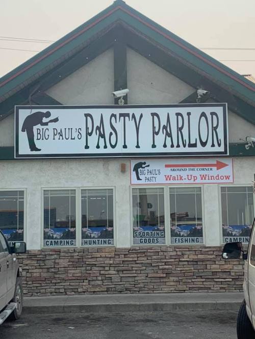 Sign for "Big Paul's Pasty Parlor" with a walk-up window, featuring outdoor activity themes like camping and fishing.