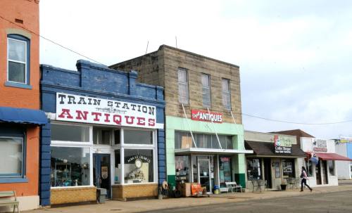 A row of antique shops in a small town, featuring colorful storefronts and a cloudy sky.