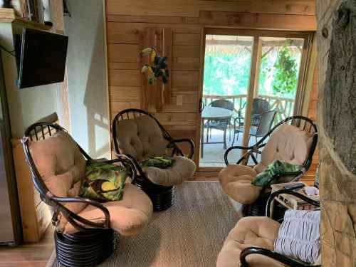 Cozy seating area with four cushioned chairs, a TV, and a view of a patio through a large window.