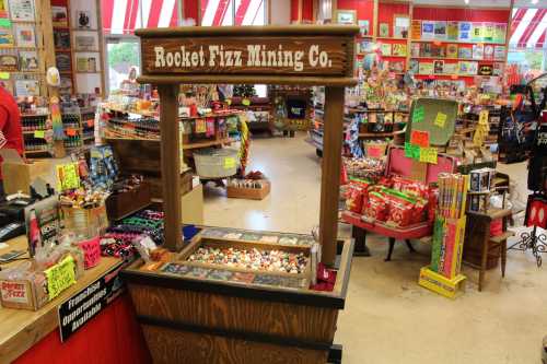 A colorful candy store interior featuring a wooden display for Rocket Fizz Mining Co. filled with various candies.