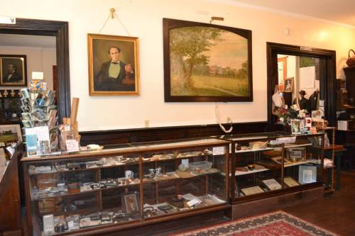 Interior of a vintage shop featuring a display case, artwork on the walls, and various items for sale.