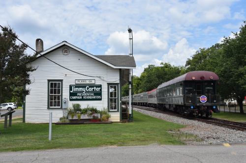 Historic building labeled "Jimmy Carter Presidential Campaign Headquarters" next to a train on tracks in Plains, GA.