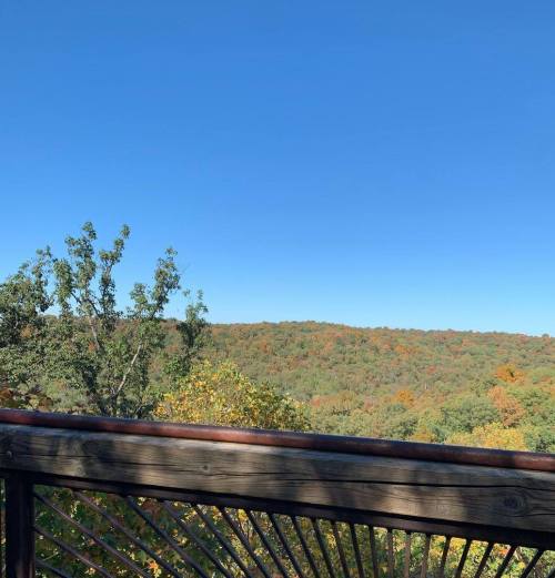 A scenic view from a wooden deck overlooking rolling hills with autumn foliage.