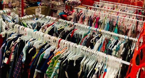 A colorful display of children's clothing hanging on racks in a store.