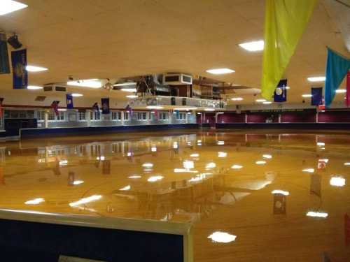 A spacious indoor rink with a shiny wooden floor and colorful banners hanging from the ceiling.