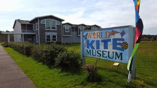 Exterior of the World Kite Museum, featuring a colorful sign and a grassy area with a building in the background.