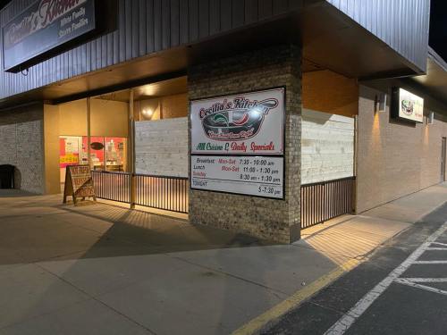 Exterior view of Cecilia's Kitchen, featuring a sign with hours and a wooden barrier, illuminated at night.