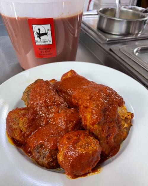 A plate of meatballs covered in red sauce, with a container of chocolate milk in the background.