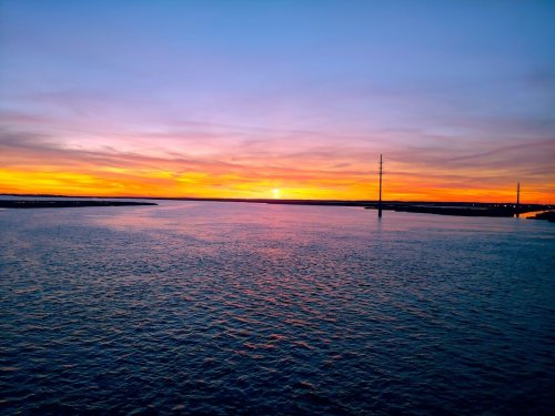 A serene sunset over calm waters, with vibrant orange and purple hues reflecting on the surface.
