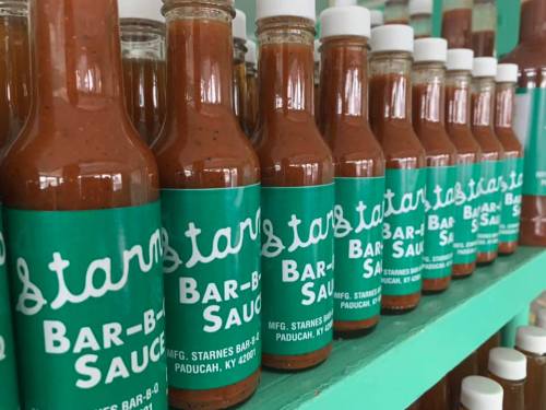Bottles of Starnes Bar-B-Q sauce lined up on a shelf, featuring a green label with white text.