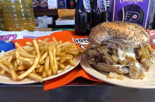 A poppy seed bun filled with beef, onions, and cheese, served with a side of crispy French fries.
