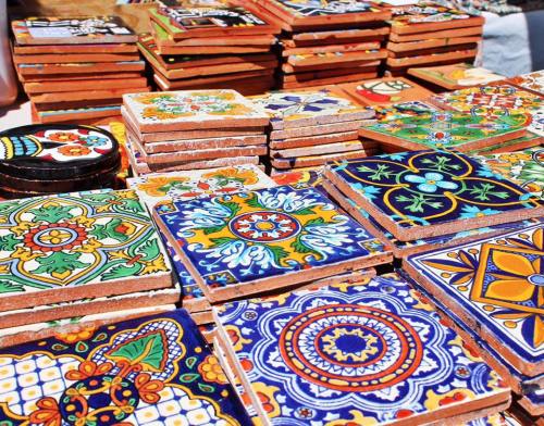 Colorful decorative tiles stacked in a market, featuring intricate patterns and vibrant designs.