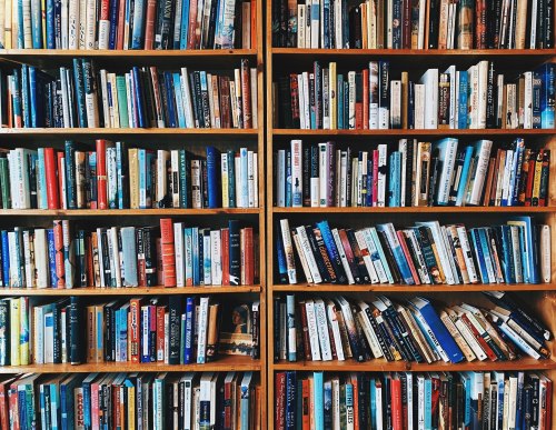 A wooden bookshelf filled with a variety of colorful books arranged neatly across multiple shelves.