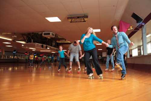 A group of people roller skating in a rink, enjoying a fun activity together on a wooden floor.