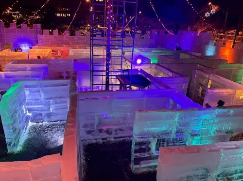 Colorful ice maze with illuminated walls and a scaffolding structure, set in a festive outdoor environment.