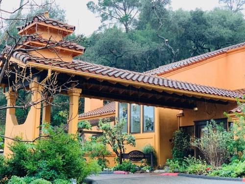 A charming building with a tiled roof and orange walls, surrounded by greenery and trees.