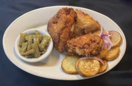 A plate of fried chicken with golden potatoes and a side of green beans.