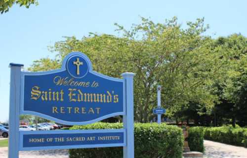 Sign welcoming visitors to Saint Edmund's Retreat, surrounded by greenery and a clear blue sky.