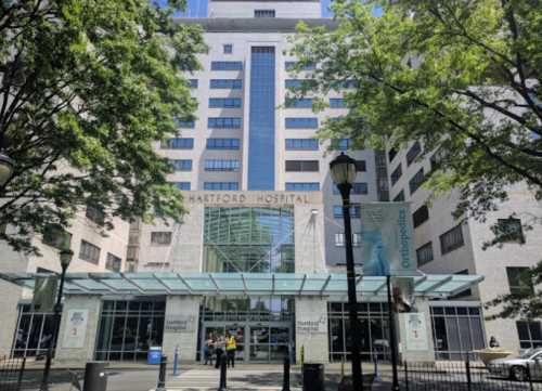 Exterior view of Hartford Hospital, featuring a modern building with large glass entrance and surrounding trees.