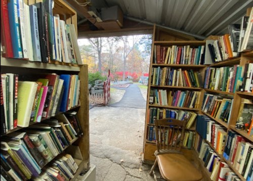 A cozy book nook with shelves of books and a view of a garden path outside.