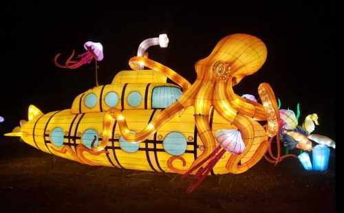 A colorful illuminated submarine with an octopus and jellyfish, glowing against a dark background.