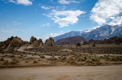 A rocky landscape with unique formations under a blue sky and distant mountains in the background.