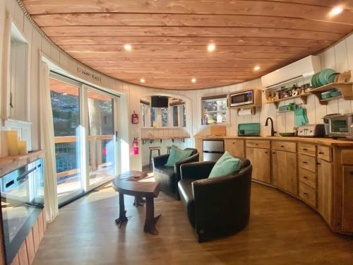 Cozy circular kitchen with wooden cabinets, modern appliances, and two black chairs, featuring large windows and natural light.