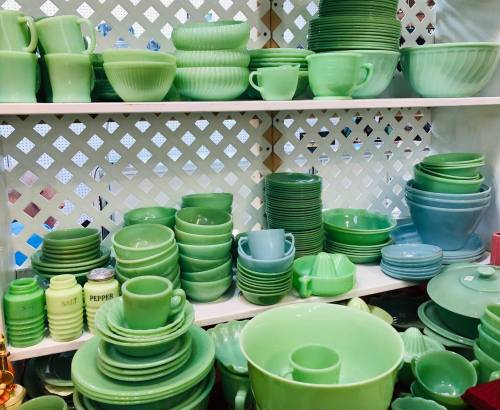 A display of various green glassware and dishware arranged on shelves, featuring bowls, cups, and decorative items.
