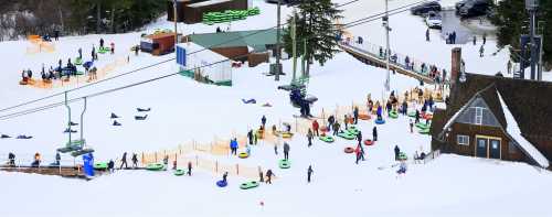 A snowy landscape with people tubing, a ski lift, and a lodge in the background.