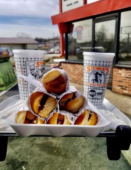 A stack of mini corn dogs in a tray, with two drinks from Stewart's in the background.