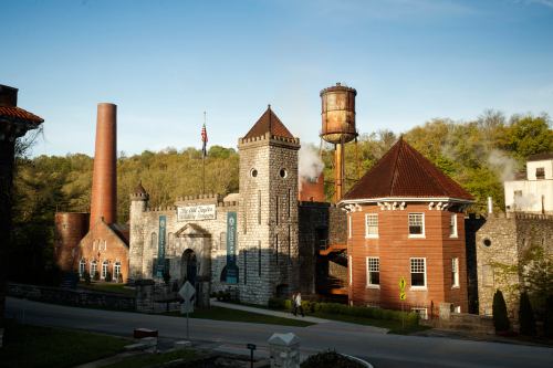 Historic buildings with a castle-like structure, a water tower, and smokestacks against a clear blue sky.