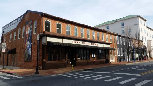 A brick building with a sign reading "Light House Bistro," located on a street with other buildings in the background.